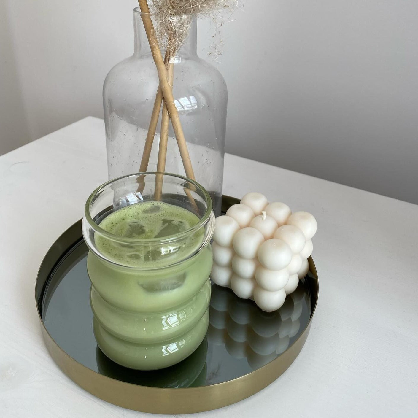 Ein stilvolles Bubble Glas | Venice Dream, präsentiert mit erfrischendem Matcha Latte auf einem Tablett mit einer Kerze und einer Trockenblume - Luxuriöses Trinkglas mit einem einzigartigen, gewölbten Bubble Design und ästhetischem Appeal. Handgefertigt für ein einzigartiges Trinkerlebnis mit warmen oder kalten Getränken. Attraktiv und edel, ideal für den täglichen Genuss oder besondere Anlässe. Erleben Sie Eleganz und Entspannung mit diesem hochwertigen, einzigartigen Glas.