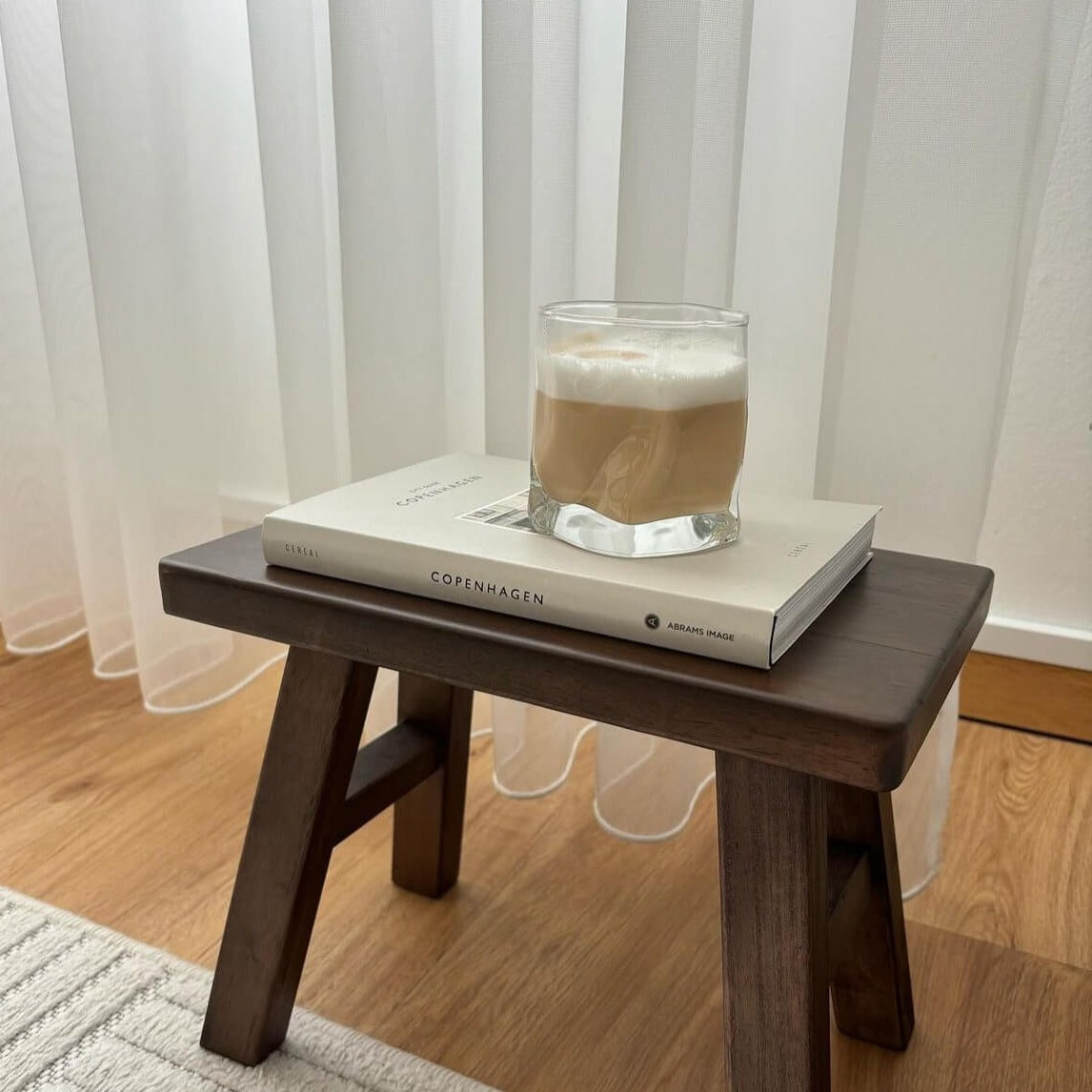 Ein ästhetisches Diamond Twist Glas, präsentiert auf einem kleinen Holztisch mit einem Buch als Unterlage und köstlichem Cappuccino darin. Luxuriöses Trinkglas mit markantem Design und ästhetischem Appeal. Perfekt für Cocktails, Whiskey oder erfrischende Getränke. Ein Blickfang auf jedem Tisch. Erleben Sie Luxus und Eleganz mit diesem hochwertigen, einzigartigen Glas. Ideal für den täglichen Gebrauch oder besondere Anlässe. Stilvoll und zeitlos gestaltet für anspruchsvolle Genießer.