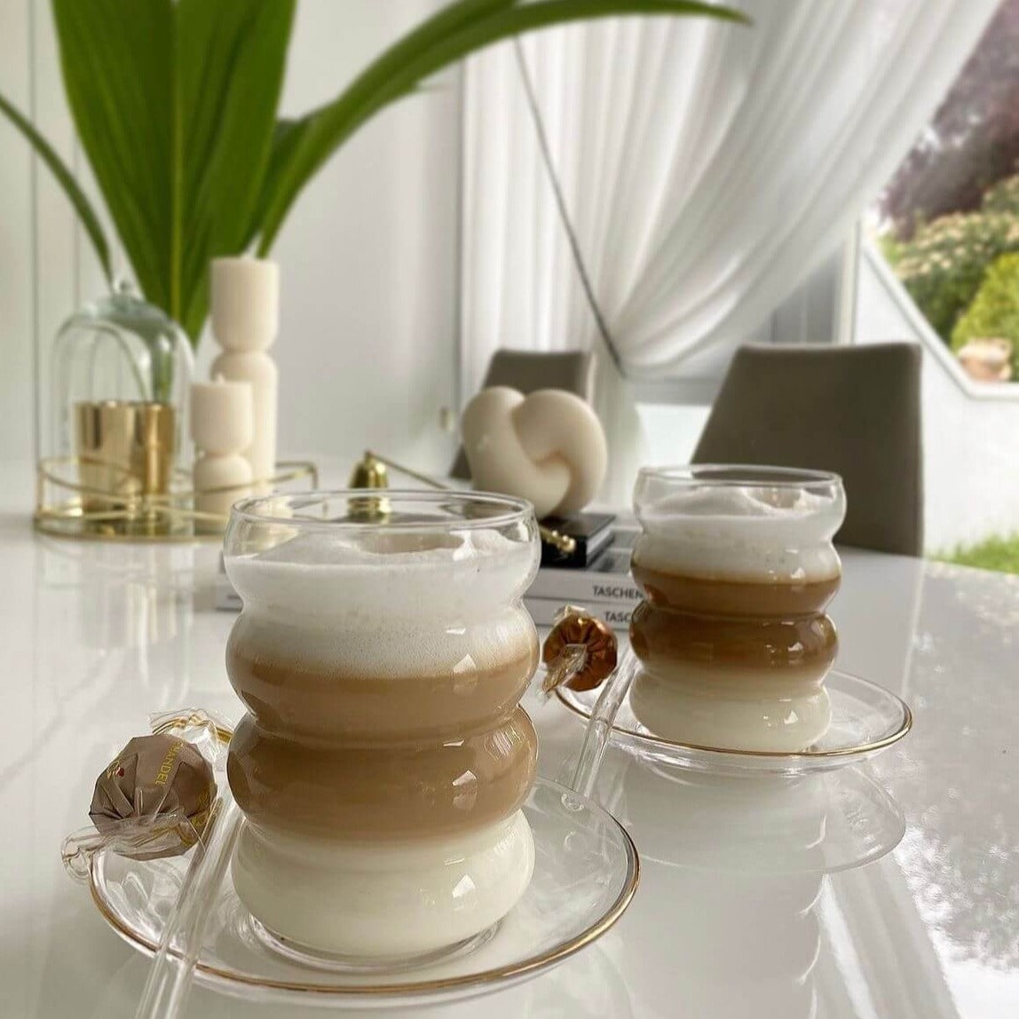 Genieße stilvoll einen köstlichen Cappuccino in unseren Bubble Gläsern | Venice Dream, präsentiert auf einem eleganten Untersetzer neben köstlicher Schokolade. Diese hochwertigen, ästhetischen Gläser sind perfekt für heiße Getränke wie Kaffee, Cappuccino und heiße Schokolade. Ihr einzigartiges Bubble-Design verleiht jedem Getränk eine besondere Ästhetik. Ein luxuriöser und eleganter Genuss für jeden Kaffeeliebhaber. Robust und stilvoll, diese Gläser sind ein Blickfang in jeder Umgebung.